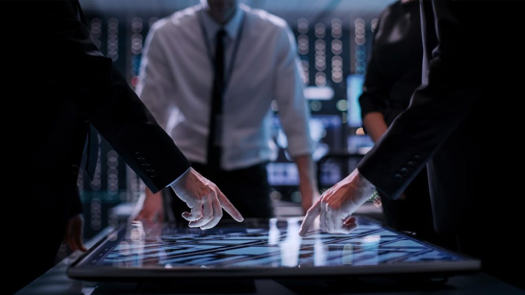A group of people in suits touching a touch screen